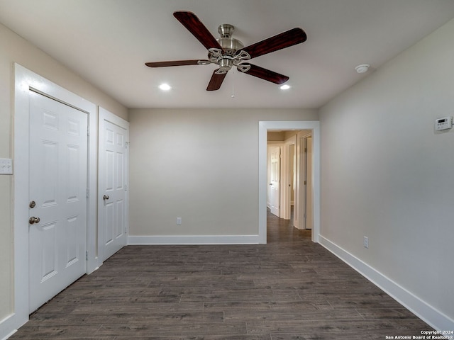 unfurnished bedroom featuring ceiling fan, dark hardwood / wood-style floors, and two closets