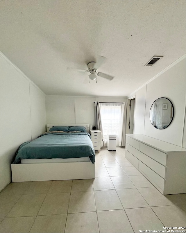 tiled bedroom featuring ceiling fan, a textured ceiling, and ornamental molding