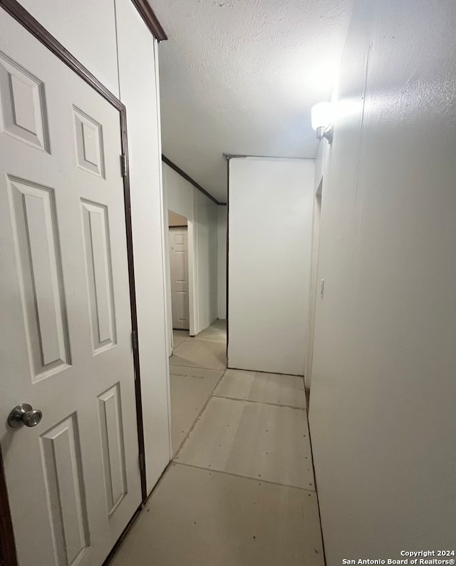 hall featuring light tile patterned floors and a textured ceiling