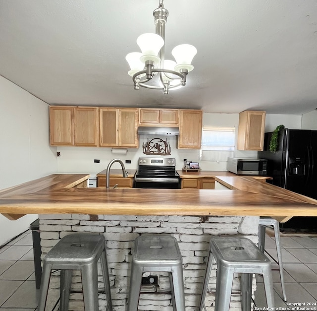 kitchen with appliances with stainless steel finishes, sink, light brown cabinets, light tile patterned floors, and a chandelier