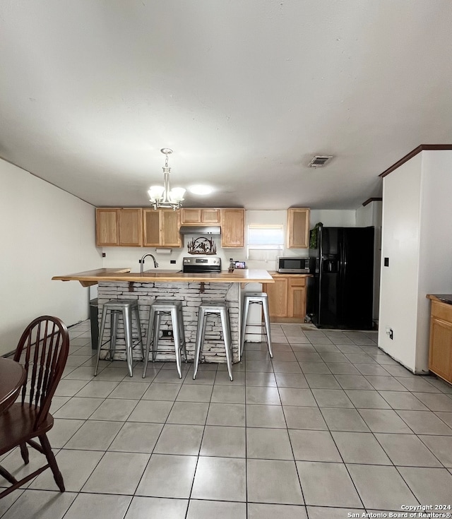 kitchen with a kitchen breakfast bar, stove, black fridge, light tile patterned floors, and a notable chandelier