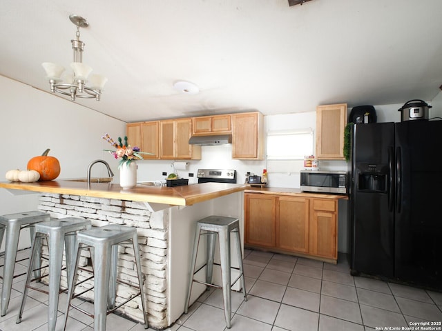 kitchen featuring hanging light fixtures, light brown cabinetry, appliances with stainless steel finishes, light tile patterned flooring, and under cabinet range hood