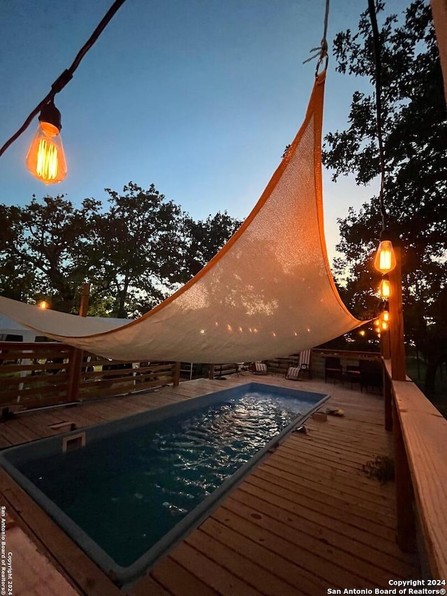 pool at dusk with a wooden deck