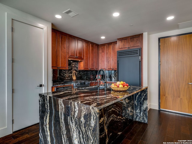 kitchen with built in fridge, dark wood-type flooring, tasteful backsplash, and sink