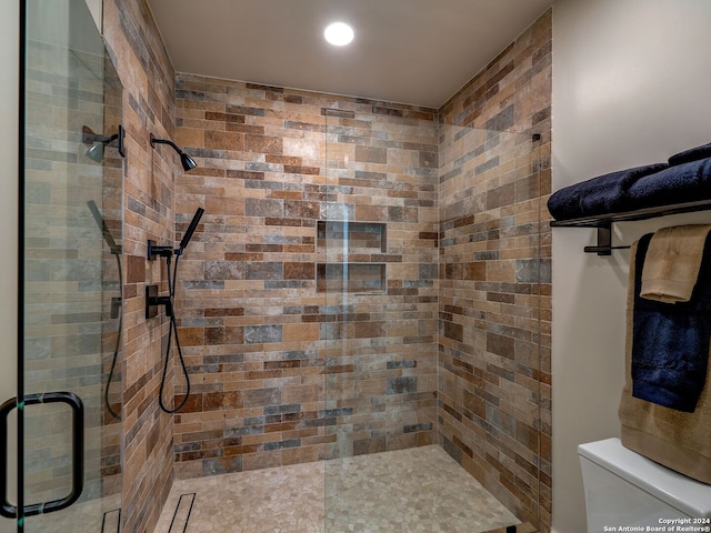 bathroom featuring toilet and a shower with door