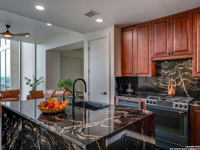 kitchen with backsplash, ceiling fan, sink, dark stone countertops, and stainless steel gas stove