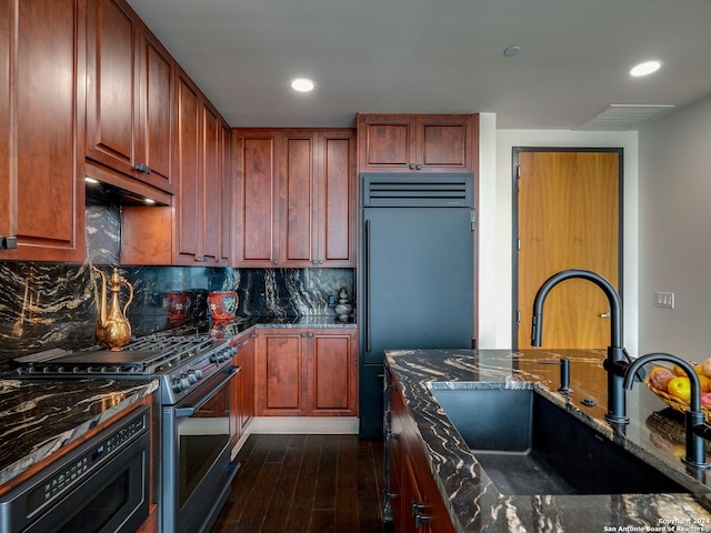 kitchen with dark hardwood / wood-style flooring, premium range hood, built in refrigerator, sink, and stainless steel gas stove