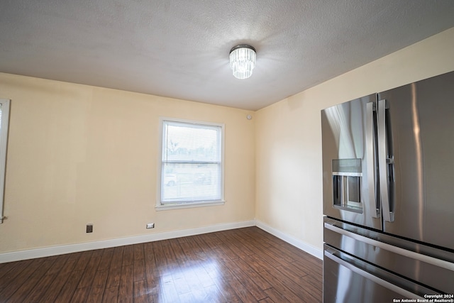 unfurnished room with dark wood-type flooring and a textured ceiling