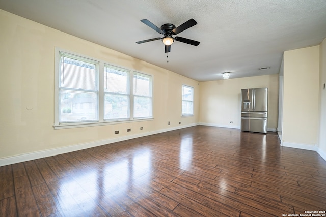 unfurnished living room with a textured ceiling, dark wood-type flooring, and ceiling fan