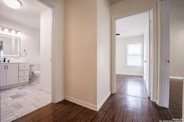 corridor featuring wood-type flooring and sink