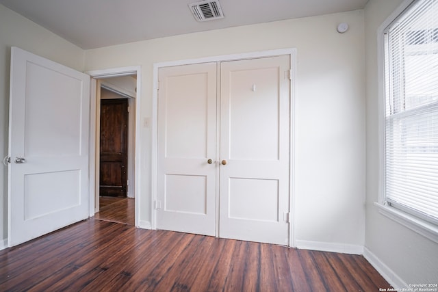 unfurnished bedroom featuring a closet and dark hardwood / wood-style flooring