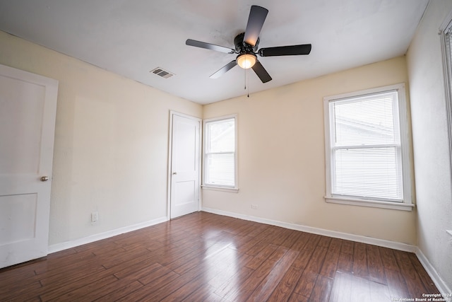 empty room featuring ceiling fan, dark hardwood / wood-style flooring, and a healthy amount of sunlight