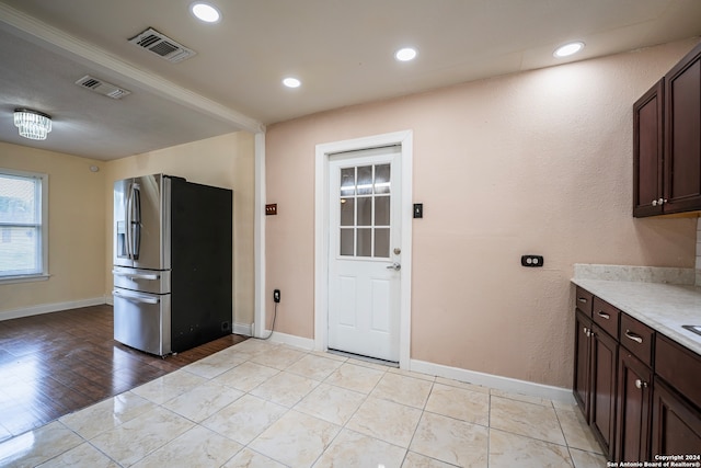 kitchen featuring stainless steel refrigerator with ice dispenser, light wood-type flooring, and dark brown cabinets