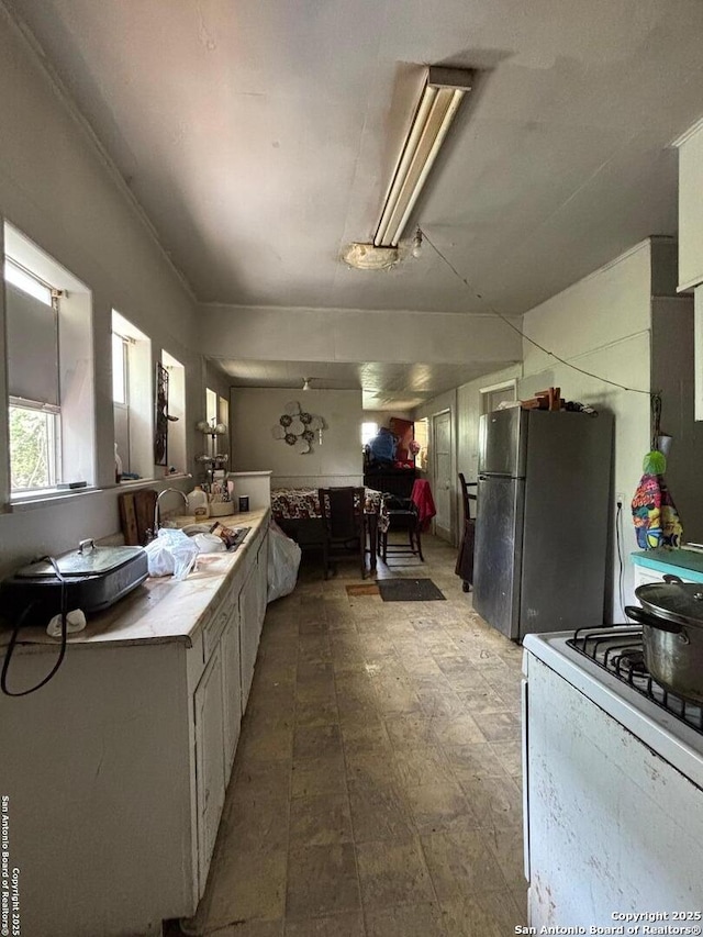 kitchen featuring light countertops, white gas range oven, and freestanding refrigerator