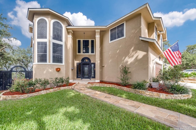 view of front of house featuring a garage, a front lawn, fence, and stucco siding