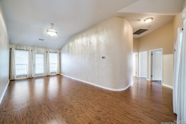 empty room with dark wood-type flooring, lofted ceiling, and an inviting chandelier