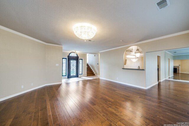 spare room featuring wood-type flooring, crown molding, a notable chandelier, and a textured ceiling