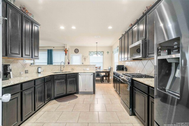 kitchen with a healthy amount of sunlight, sink, light stone countertops, and appliances with stainless steel finishes