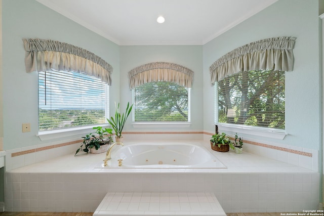 bathroom featuring a wealth of natural light, a relaxing tiled tub, and ornamental molding