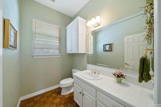 bathroom featuring vanity, toilet, plenty of natural light, and parquet floors