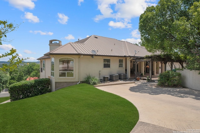 rear view of property featuring cooling unit and a lawn