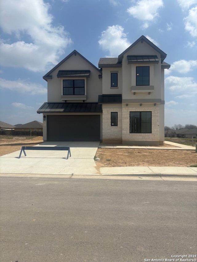 view of front of home with driveway, a standing seam roof, stone siding, a garage, and metal roof