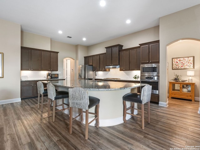 kitchen featuring stainless steel appliances, sink, dark hardwood / wood-style floors, an island with sink, and a kitchen breakfast bar