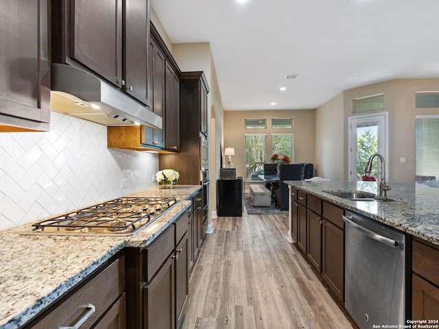 kitchen with light hardwood / wood-style flooring, appliances with stainless steel finishes, light stone counters, sink, and decorative backsplash