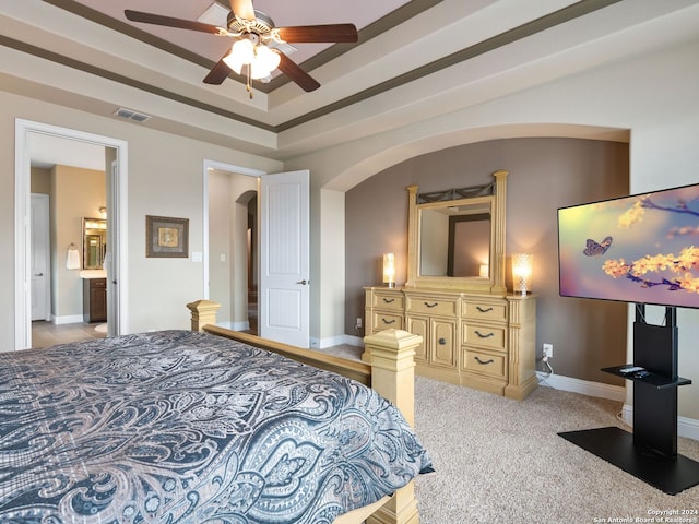 bedroom featuring ceiling fan, ensuite bath, and light carpet