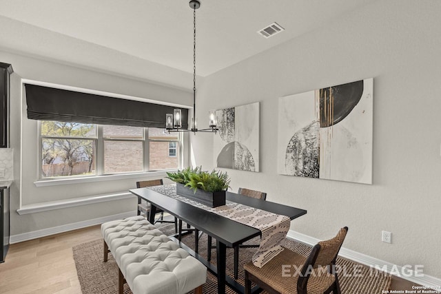 dining space with light hardwood / wood-style flooring and an inviting chandelier