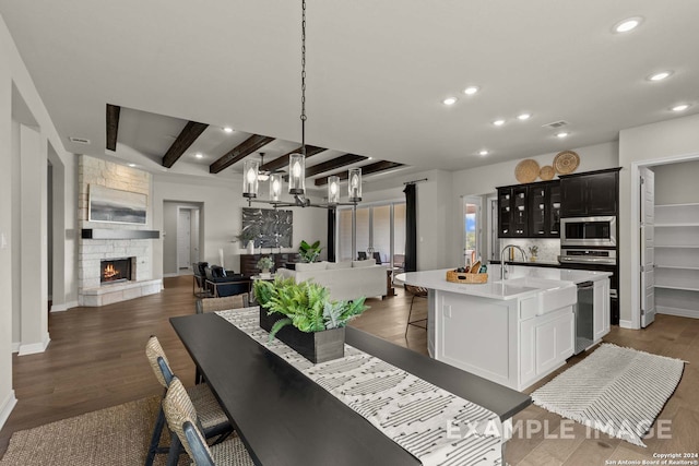 dining room with a notable chandelier, dark hardwood / wood-style floors, beamed ceiling, and a fireplace