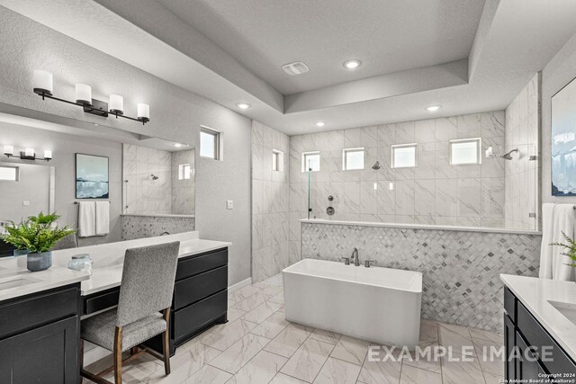 bathroom with tile walls, independent shower and bath, a tray ceiling, and vanity