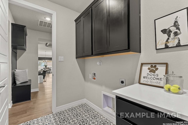 washroom with hookup for a washing machine, an inviting chandelier, light wood-type flooring, hookup for an electric dryer, and cabinets