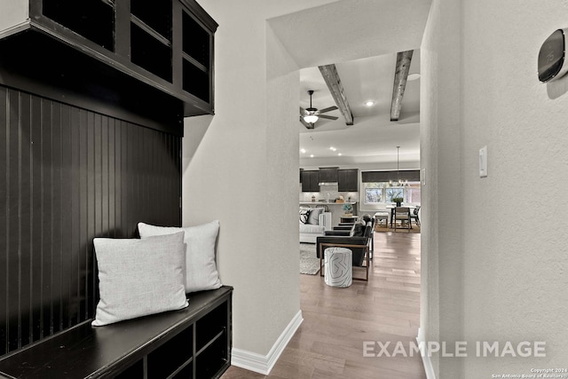 mudroom featuring ceiling fan with notable chandelier, wood-type flooring, and beam ceiling