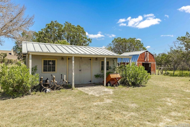 rear view of property featuring an outbuilding, a lawn, a gambrel roof, a standing seam roof, and metal roof