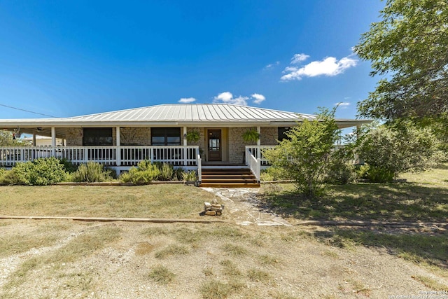 view of front of home with covered porch, metal roof, brick siding, and a standing seam roof