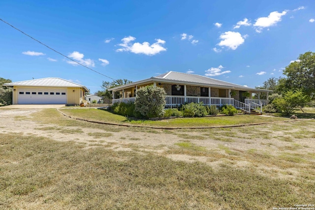 view of front of property with metal roof, covered porch, a garage, an outdoor structure, and driveway