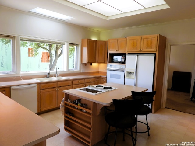 kitchen with white appliances, a kitchen island, a breakfast bar, and sink