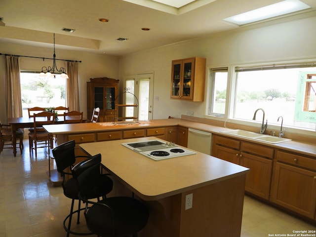 kitchen with hanging light fixtures, a kitchen bar, white appliances, and sink