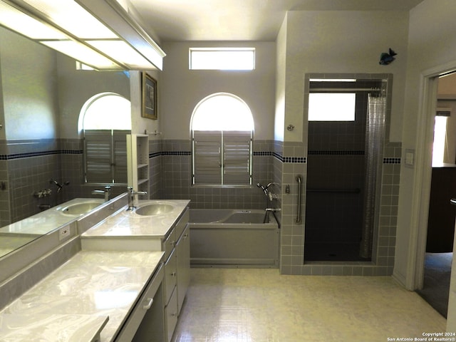 bathroom with vanity, tile walls, and shower with separate bathtub