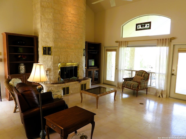 living room featuring plenty of natural light, ceiling fan, a stone fireplace, and high vaulted ceiling