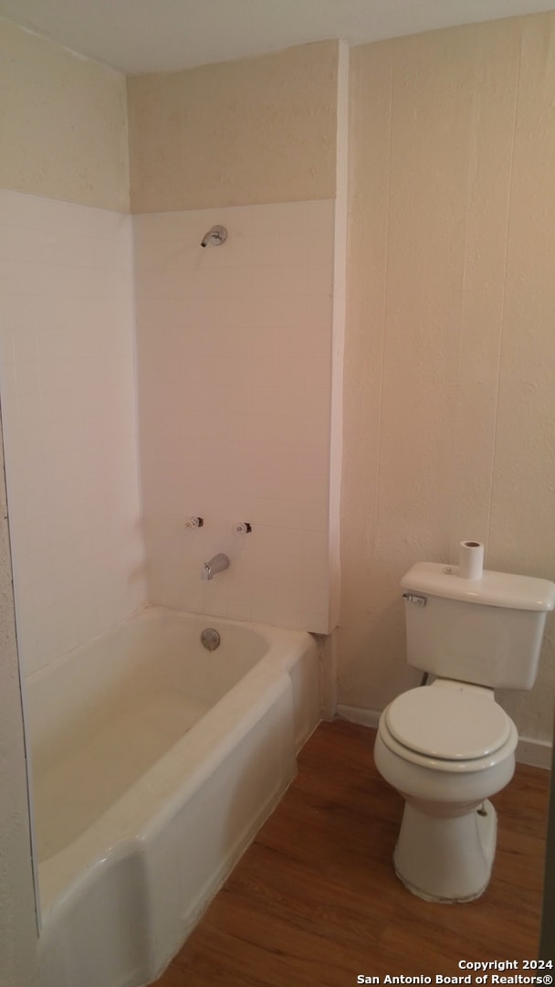 bathroom with bathing tub / shower combination, toilet, and hardwood / wood-style floors