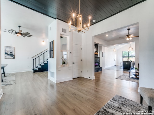 interior space with ceiling fan with notable chandelier, wood ceiling, and light hardwood / wood-style flooring