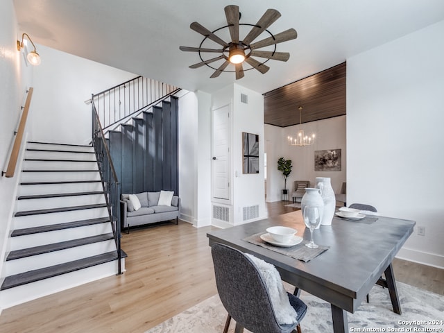 dining area with ceiling fan with notable chandelier and light hardwood / wood-style flooring