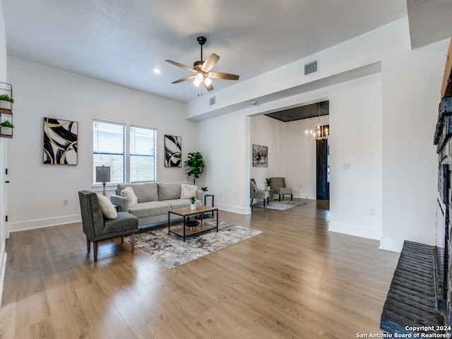 living room featuring wood-type flooring and ceiling fan with notable chandelier