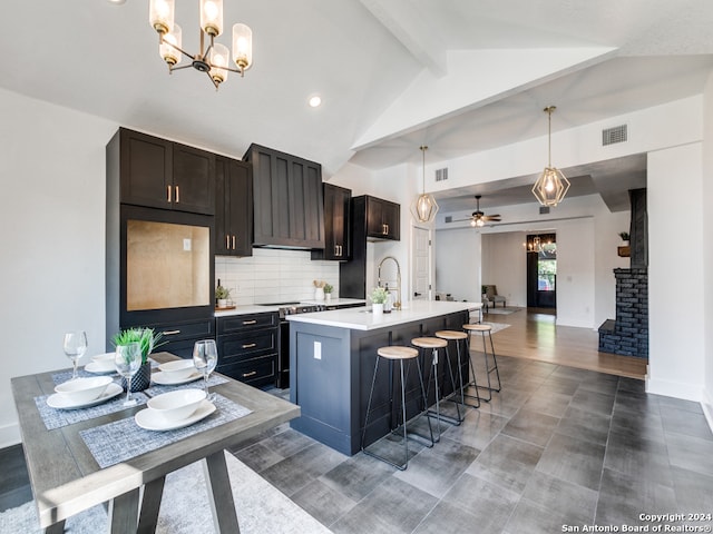 kitchen with lofted ceiling with beams, ceiling fan with notable chandelier, an island with sink, stainless steel electric range oven, and hanging light fixtures