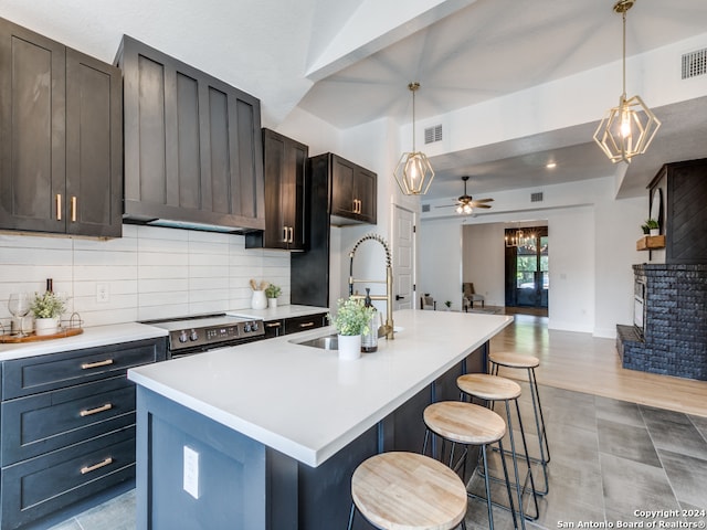 kitchen featuring an island with sink, ceiling fan, decorative light fixtures, and sink