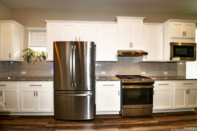 kitchen featuring dark stone countertops, white cabinetry, decorative backsplash, dark hardwood / wood-style floors, and appliances with stainless steel finishes