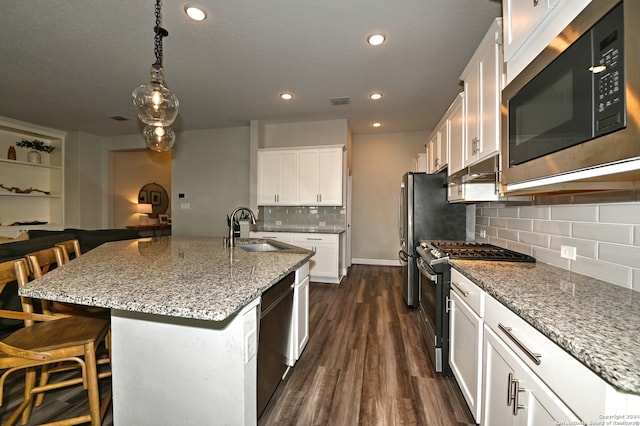 kitchen featuring white cabinets, appliances with stainless steel finishes, sink, an island with sink, and a breakfast bar area