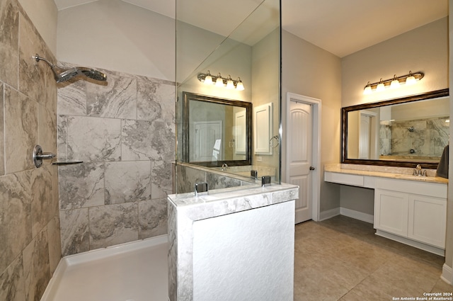 bathroom featuring vanity, a tile shower, and tile patterned flooring